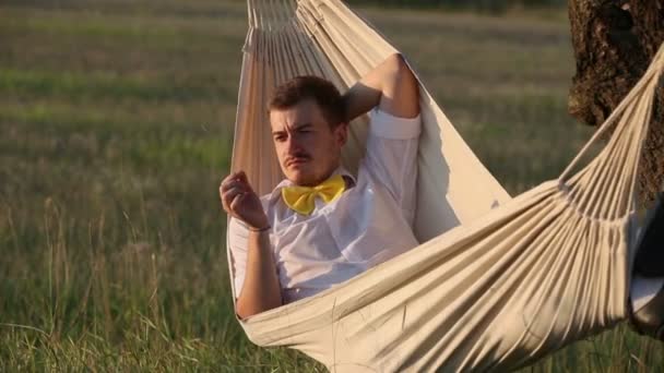 Mladý muž houpat v houpací síti při západu slunce — Stock video