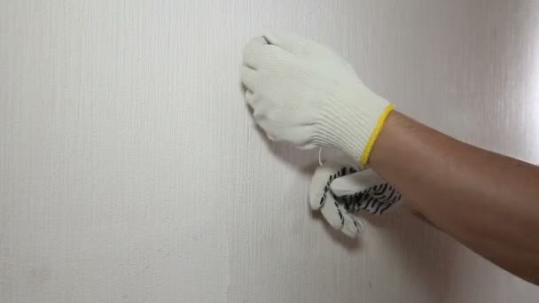 Man in glove showing how to remove old wallpaper — Stock Video