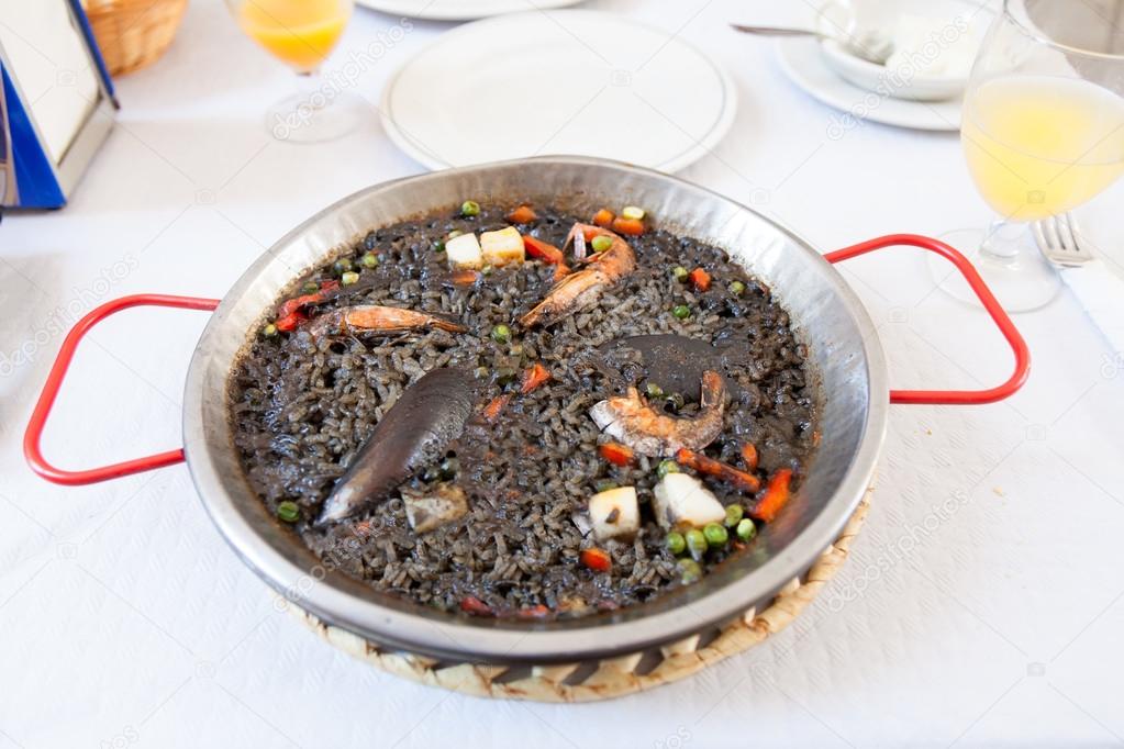 Paella negra on the pan, white table