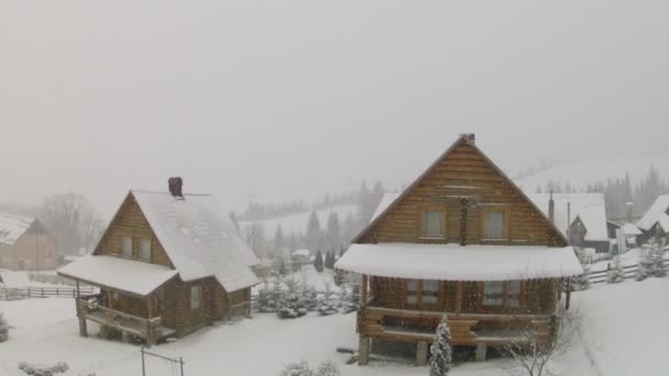 Casas de madera y nieve cayendo con cámara móvil — Vídeos de Stock