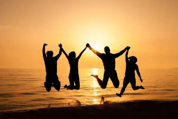 Vier vrienden springen op het strand Stockfoto