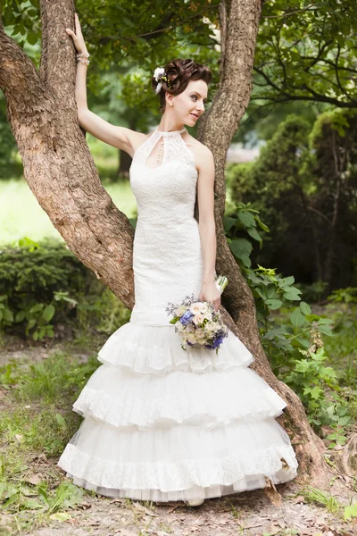 Jeune mariée avec bouquet près de tre — Photo