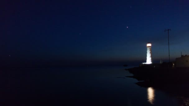 Маяк на краю воды возле моря ночью, время пролетело — стоковое видео