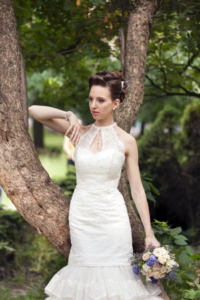 Jeune mariée avec bouquet près de l'arbre — Photo