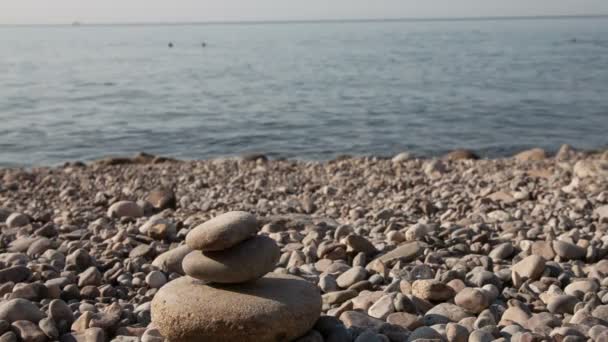 Man building stone pyramid on the sea beach — Stock Video