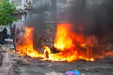 Burning car in the center of city during unrest clipart