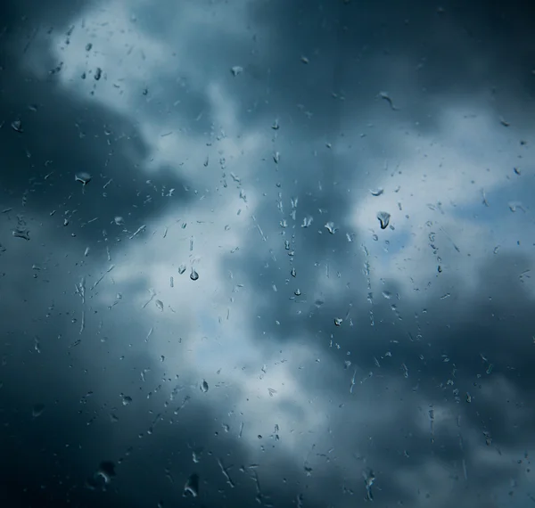 Rain drops on window across clouds — Stock Photo, Image