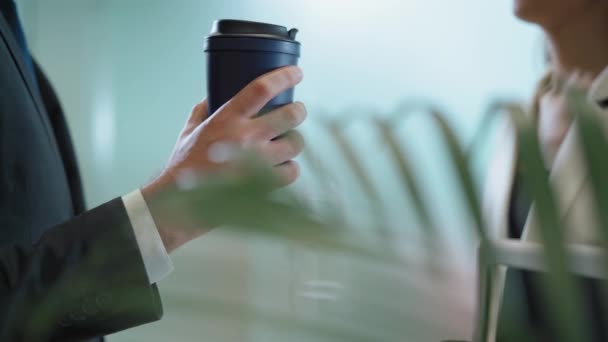 Üzleti kávészünet üzletemberek. Egy férfi kéz kávét tart egy eldobható pohárban. üzleti partnerek megvitatják azokat a kérdéseket a szünet alatt, amelyek a cég lobbyjában állnak. 4K felvétel — Stock videók