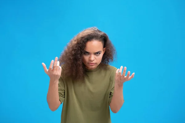 Δυσάρεστη Αφροαμερικανή κοπέλα της χιλιετίας που αναστατώθηκε σήκωσε τα χέρια ψηλά δείχνοντας απογοητευμένη μπροστά στην κάμερα φορώντας ένα μπλουζάκι με ελιές απομονωμένο σε μπλε φόντο. Ανθρώπινα συναισθήματα, έννοια της έκφρασης του προσώπου — Φωτογραφία Αρχείου