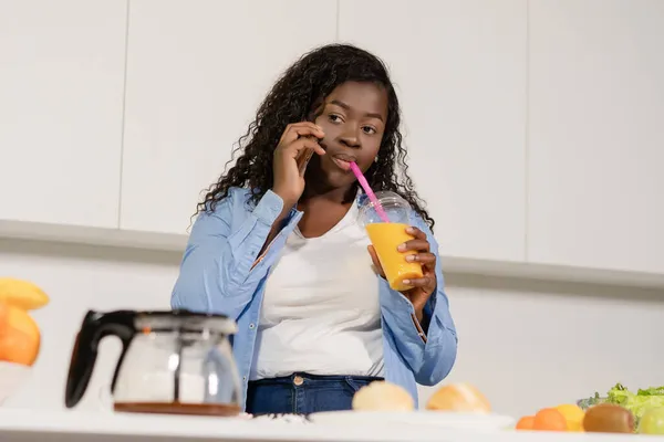 非洲妇女在她的厨房里一边说一边喝橙汁。特写。白人背景 — 图库照片