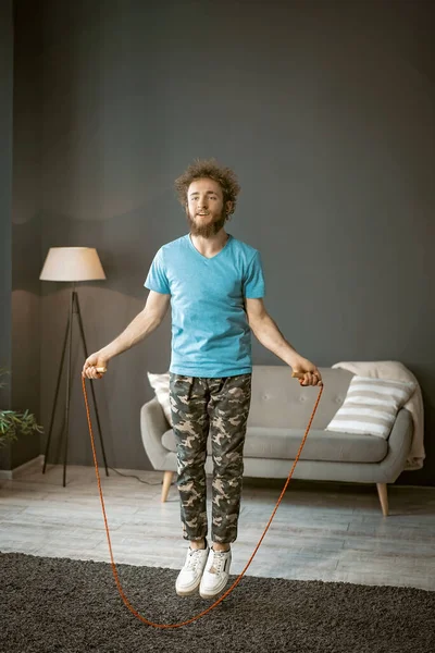 Sporty Male Jumping Rope in Fast Rhythm on the Carpet in his Living Room (dalam bahasa Inggris). Dia menemukan olahraga. — Stok Foto