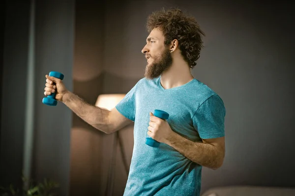 Slim White Man Doing His Morning Exercises with Dumbbells. El joven quiere mejorar su salud. Fondo gris — Foto de Stock