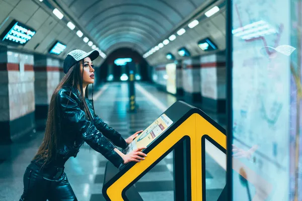 패션 스타일 모델 20 대 여성 캐릭터가 지하철 역 승강장에서 노래하는 모습. 멋진 브루넷 여인이 빈 역 승강장에 있는 메트로 맵을 보고 있다. 클로즈업 — 스톡 사진