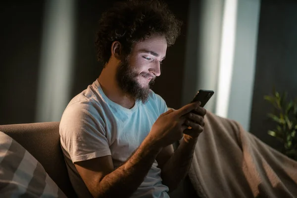 Nice Guy SMS ke pacarnya oleh Smartphone-nya di malam hari. Sebelum pergi ke tempat tidur, dia mengirim surat ke saudarinya. Close-up. — Stok Foto