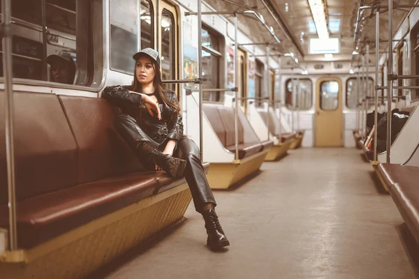 Brutal Femme dans une veste en cuir, pantalons en cuir et bottes de cheville est assis seul dans un wagon de train. Image tonique. Gros plan — Photo