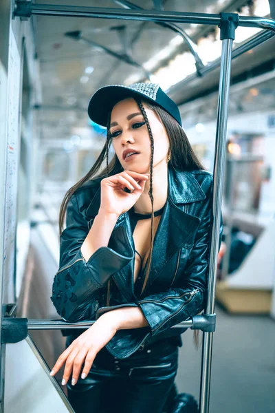 Heerlijke vrouw in stijlvolle trendy kleding staat in een prachtige pose in een metro auto. disco meisje keert 's avonds terug van een feestje met de metro. Close-up Portret — Stockfoto