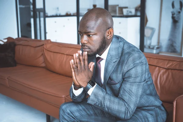 Geschäftsmann beim Nachdenken über Strategien zur Unternehmensentwicklung. Schöner Mann im klassischen Anzug sitzt auf einem Ledersofa im Flur seines modernen Büros. Nahaufnahme — Stockfoto