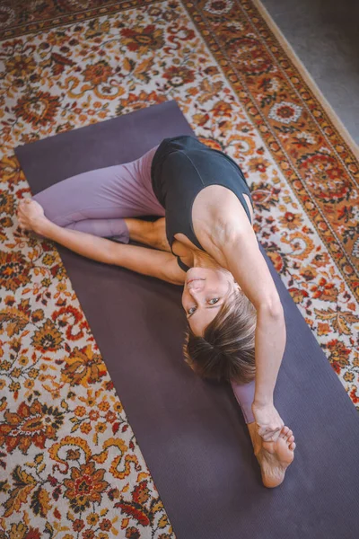 Woman is engaged in yoga. Stretching while looking at the camera. The concept of self-love, care, positive, energy. — Stock Fotó