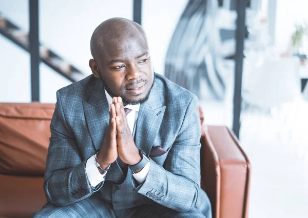 Serious Lawyer with Piercing Gaze in Formal Suit Sits on Couch in his Office in a Futuristic Style. Male Model Puts his Palms of Hands Together. Close-up Portrait. Copy Space — Stock Photo, Image