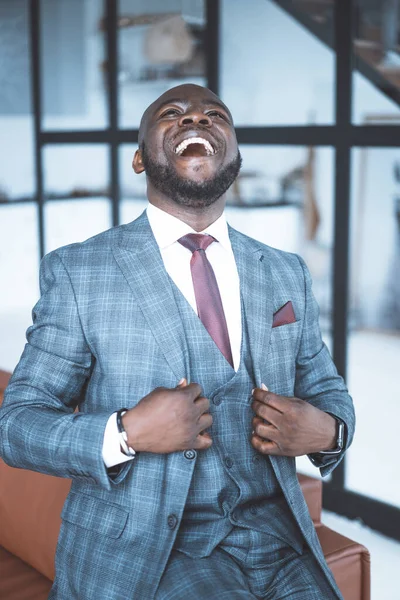 Framgångsrik affärsman i formell kostym skrattar med huvudet kastat tillbaka. African Businessman Nöjd med en lyckad deal. Tredelad kostym. Närbild Porträtt. Stor fönsterbakgrund — Stockfoto