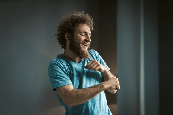 Coily Guy in een blauw T-shirt en een Tattoo op zijn nek maakt grappige bewegingen door zijn handen. Jongeman dansend in de kamer thuis. Begrepen Ruimte. Close-up — Stockfoto