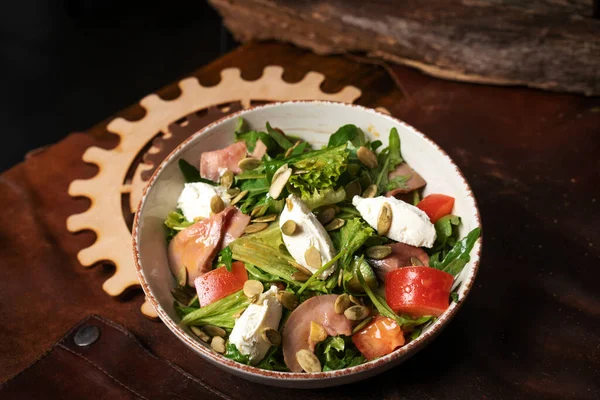 Sebzeli taze vegan salatası, Balık, peynir, yumurta, kabak tohumu, Arugula in White Seramic Bowl on a Leather Apron. Üst görünüm — Stok fotoğraf