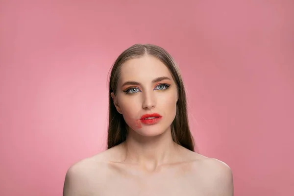 Maquiagem confusa de um olhar modelo de beleza desapontado isolado no fundo rosa em estúdio. Lábios vermelhos estragados. Beleza criativa compõem modelo com cabelo longo e saudável. Conceito de beleza — Fotografia de Stock