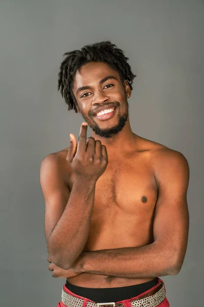 Modèle masculin africain torse nu gesticulant sur la caméra souriant avec les bras croisés. Un homme afro-américain à moitié nu posant sur une caméra isolée sur fond gris. Homme afro-américain topless — Photo