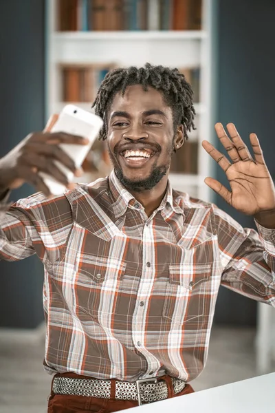 Étudiant afro-américain ayant un appel vidéo ou de prendre selfie tenir son téléphone en main devant. Portrait de l'homme heureux gestuelle regardant la caméra du smartphone. Concept de médias sociaux — Photo