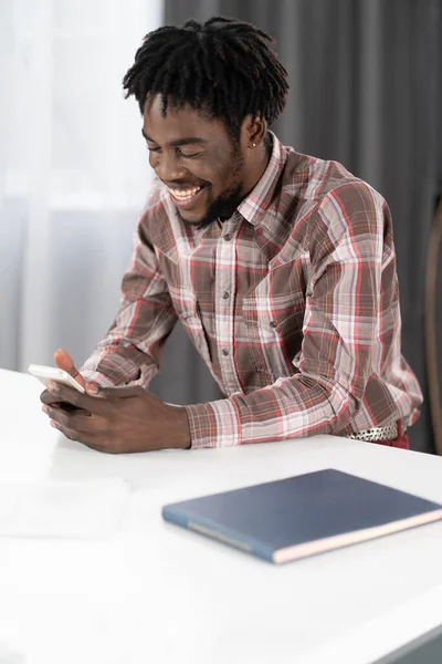 Afro-américain gars sourire lire du texte sur smartphone ou avoir un appel vidéo ou de prendre selfie. Portrait de l'homme heureux gestuelle regardant la caméra du smartphone. Concept de médias sociaux — Photo