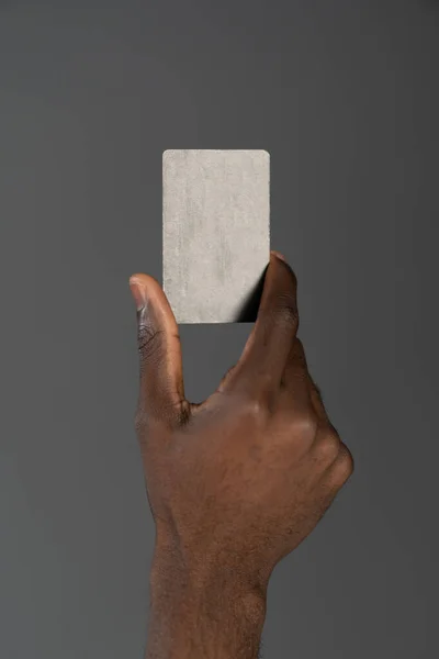 Homme afro-américain tenant la main carte de débit ou de crédit à la main isolé sur fond gris. Concept d'entreprise financière. Carte bancaire en homme africain isolé à la main sur fond gris — Photo