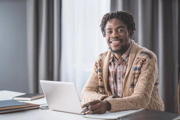 Afrikai amerikai diák tanulmány otthonról laptoppal ül az ablak mellett. Fiatal vállalkozó dolgozik a laptopján otthon. Afrikai-amerikai diák tanulmány otthon zárlat alatt — Stock Fotó