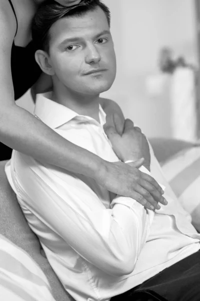 Amor y pasión mujer abraza al hombre. Marido y esposa después de una cena romántica. Romance en las relaciones, amor y ternura. Hermosa pareja joven en el interior del hogar. Foto en blanco y negro — Foto de Stock