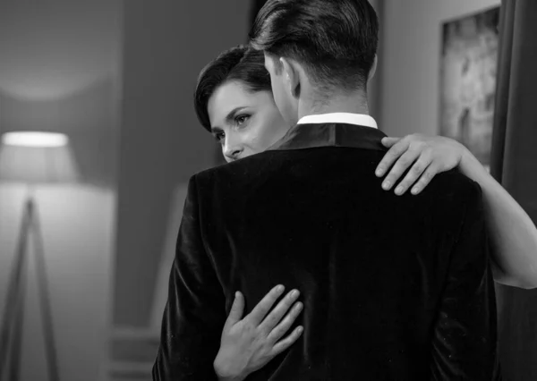 춤에 대한 열정을 가진 여자는 카메라 앞에 서 있는 남자를 껴안는다. 낭만적 인 저녁 식사 후 남편 과 아내. 관계 에서의 연애. 아름다운 젊은 커플 이 집 안에 있습니다. 흑백 사진 — 스톡 사진