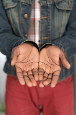 Begging hands of a poor man concept. Open hands of a young african american man wearing denim jacket. Young african american man with outstretched hands begging for money for life clipart