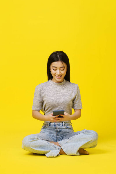 Asian Young Girl Sitting Floor Holding Smartphone Texting Shopping Online Royalty Free Stock Images