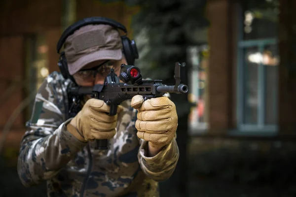 Private military contractor at tactical training course. Shooter with a gun in military uniform. Police training in shooting gallery with weapon. Shotgun weapon action course. Outdoor shooting range.