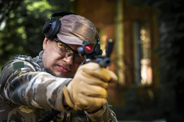 Young man at civil police tactical training course. Man with a gun in military uniform tactical hearing protector headset. Police training in shooting gallery with weapon. Selective focus on hand.