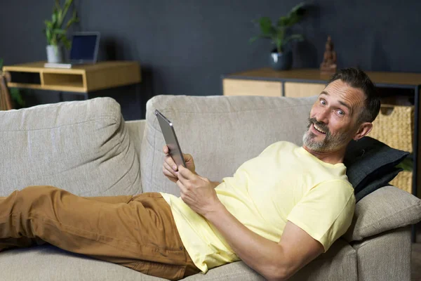 Terbaring Sofa Pria Paruh Baya Menggunakan Tablet Digital Untuk Membaca — Stok Foto