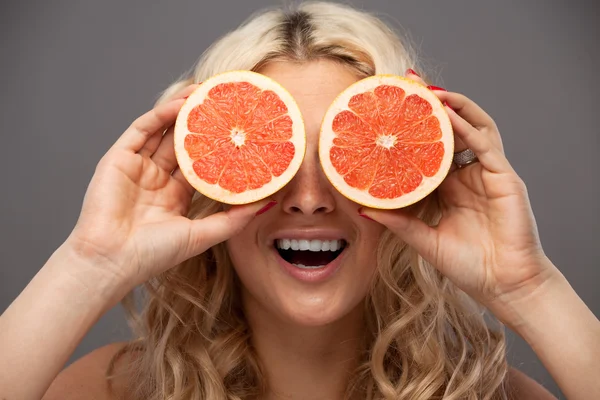 Mulher sorridente segurando duas toranjas nas mãos — Fotografia de Stock