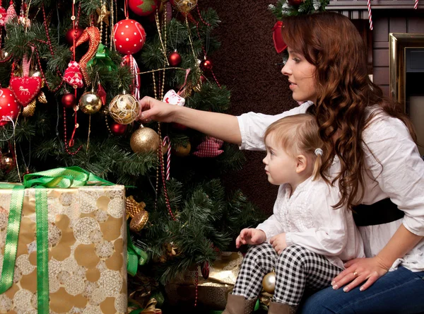 Feliz madre decorando el árbol de Navidad con su bebé —  Fotos de Stock