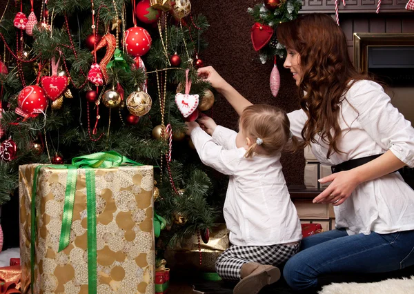 Feliz madre decorando el árbol de Navidad con su bebé — Foto de Stock