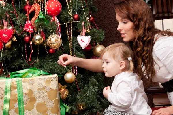 Feliz madre decorando el árbol de Navidad con su bebé — Foto de Stock