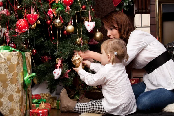 Feliz madre decorando el árbol de Navidad con su bebé — Foto de Stock