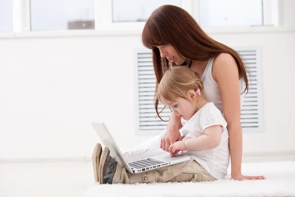 Lycklig ung mor och hennes dotter använder en bärbar dator — Stockfoto