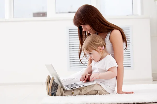 快乐的年轻妈妈和她的女儿用笔记本电脑 — 图库照片