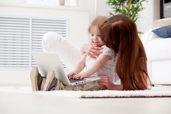 Glückliche junge Mutter und ihre Tochter mit einem Laptop — Stockfoto