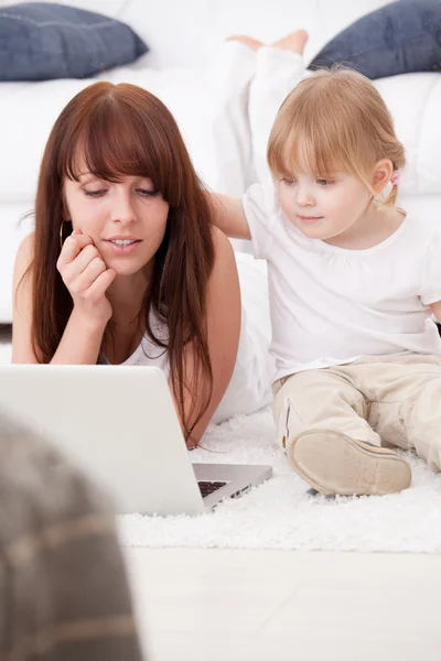 Jovem mãe feliz e sua filha usando um laptop — Fotografia de Stock