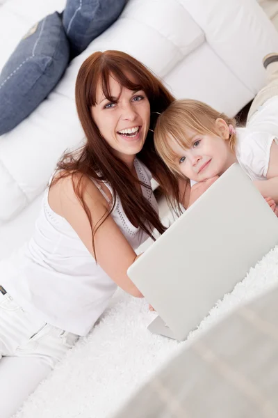 Jovem mãe feliz e sua filha usando um laptop — Fotografia de Stock