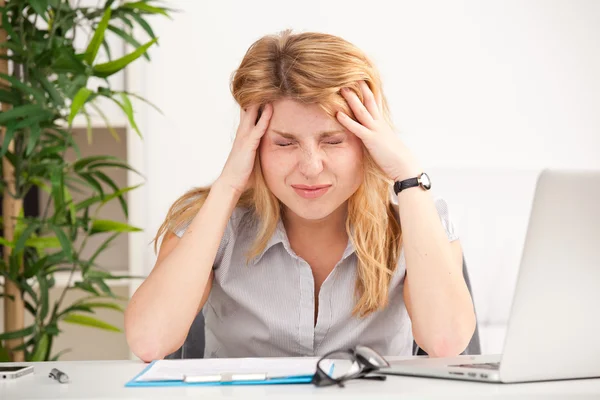 Vrouw met hoofdpijn zitten aan de tafel Stockafbeelding